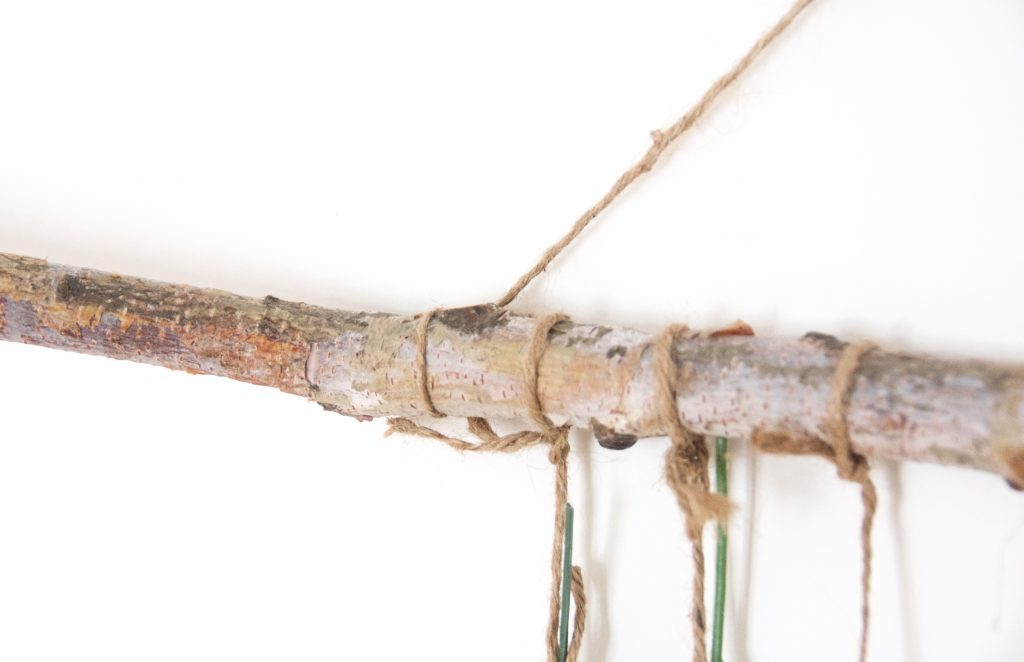 DIY floral wall hanging Tie the longer piece of twine you set aside on the ends of the branch
